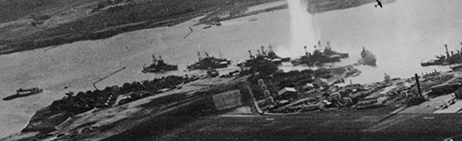 Battleship Row, seen from an attacking Japanese plane. Ford Island is in the foreground.