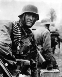 A Nazi soldier, heavily armed, carries ammunition boxes forward with companion in territory taken by their counter-offensive in this scene from captured German film. Belgium, December 1944.