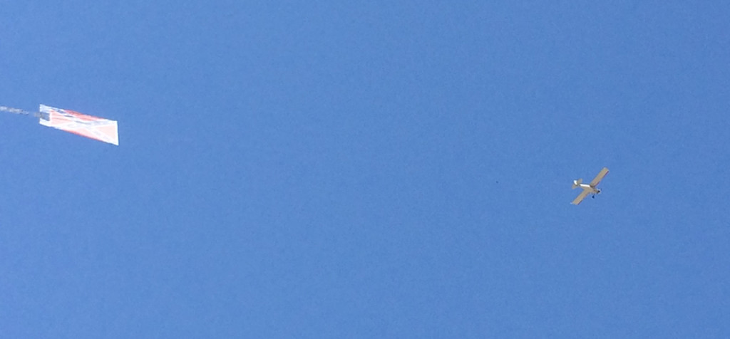 In this one you can see the plane, but the sun's glare obscures the flag, and I missed the words (I had trouble aiming with the sun in my eyes).