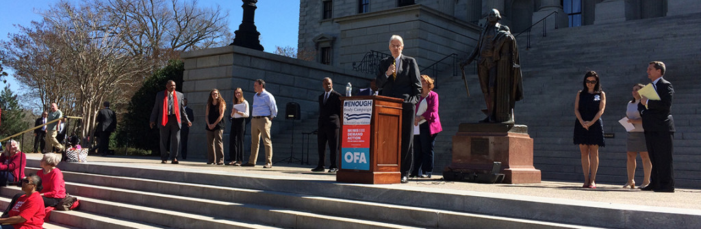 Phil Noble speaks to the rally. That's James Smith with Mandy Powers Norrell to the right.